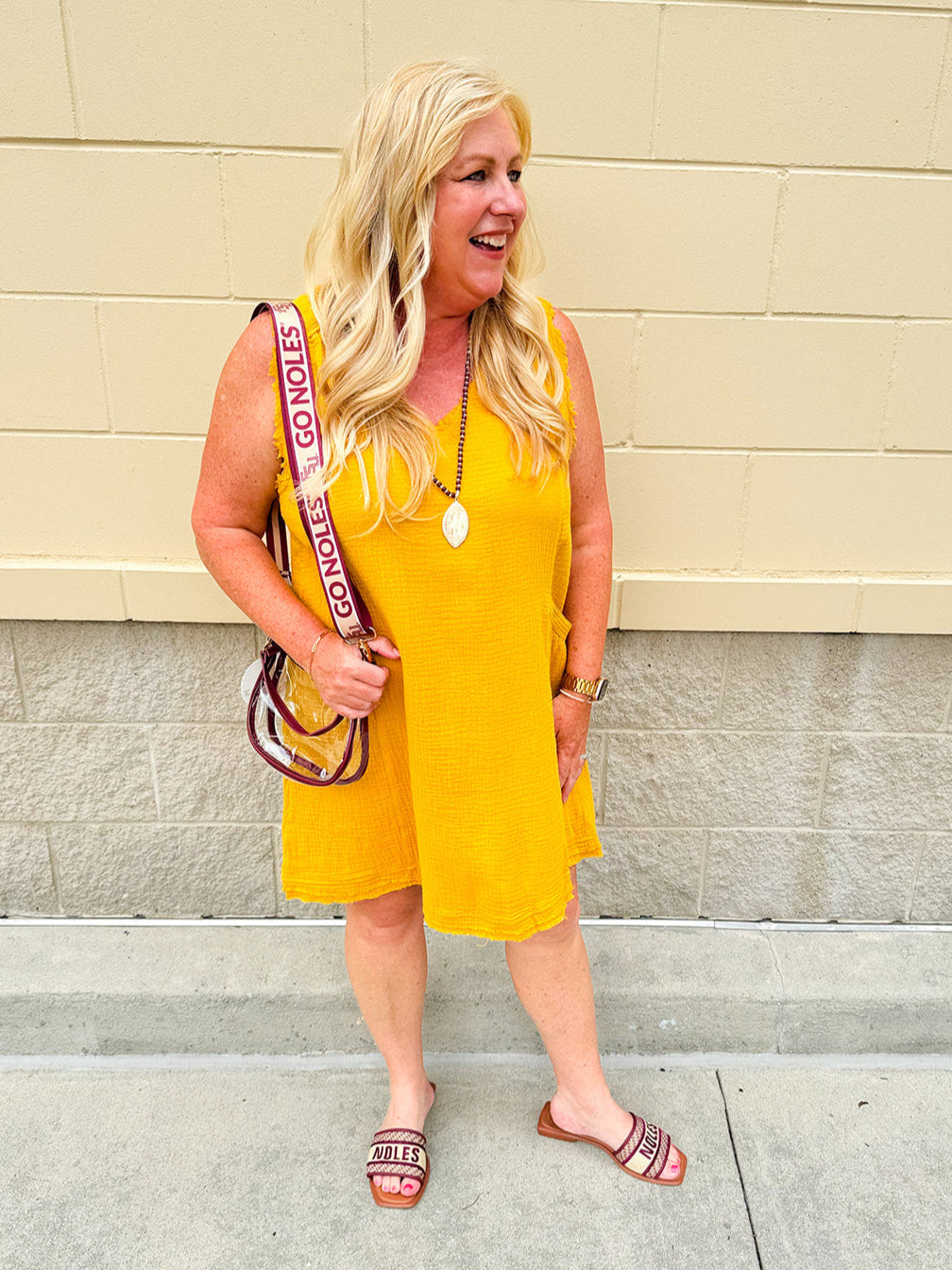 Sleeveless mustard cotton gauze dress with V-neckline, raw frayed edges, and front pockets. Lightweight and casual—ideal for Gameday or fall outings.