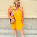 Sleeveless mustard cotton gauze dress with V-neckline, raw frayed edges, and front pockets. Lightweight and casual—ideal for Gameday or fall outings.