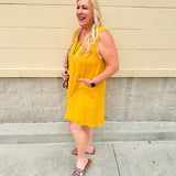 Sleeveless mustard cotton gauze dress with V-neckline, raw frayed edges, and front pockets. Lightweight and casual—ideal for Gameday or fall outings.