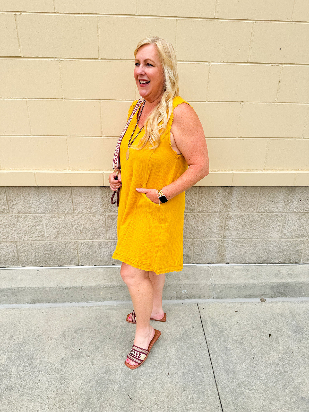 Sleeveless mustard cotton gauze dress with V-neckline, raw frayed edges, and front pockets. Lightweight and casual—ideal for Gameday or fall outings.