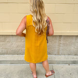 Sleeveless mustard cotton gauze dress with V-neckline, raw frayed edges, and front pockets. Lightweight and casual—ideal for Gameday or fall outings.
