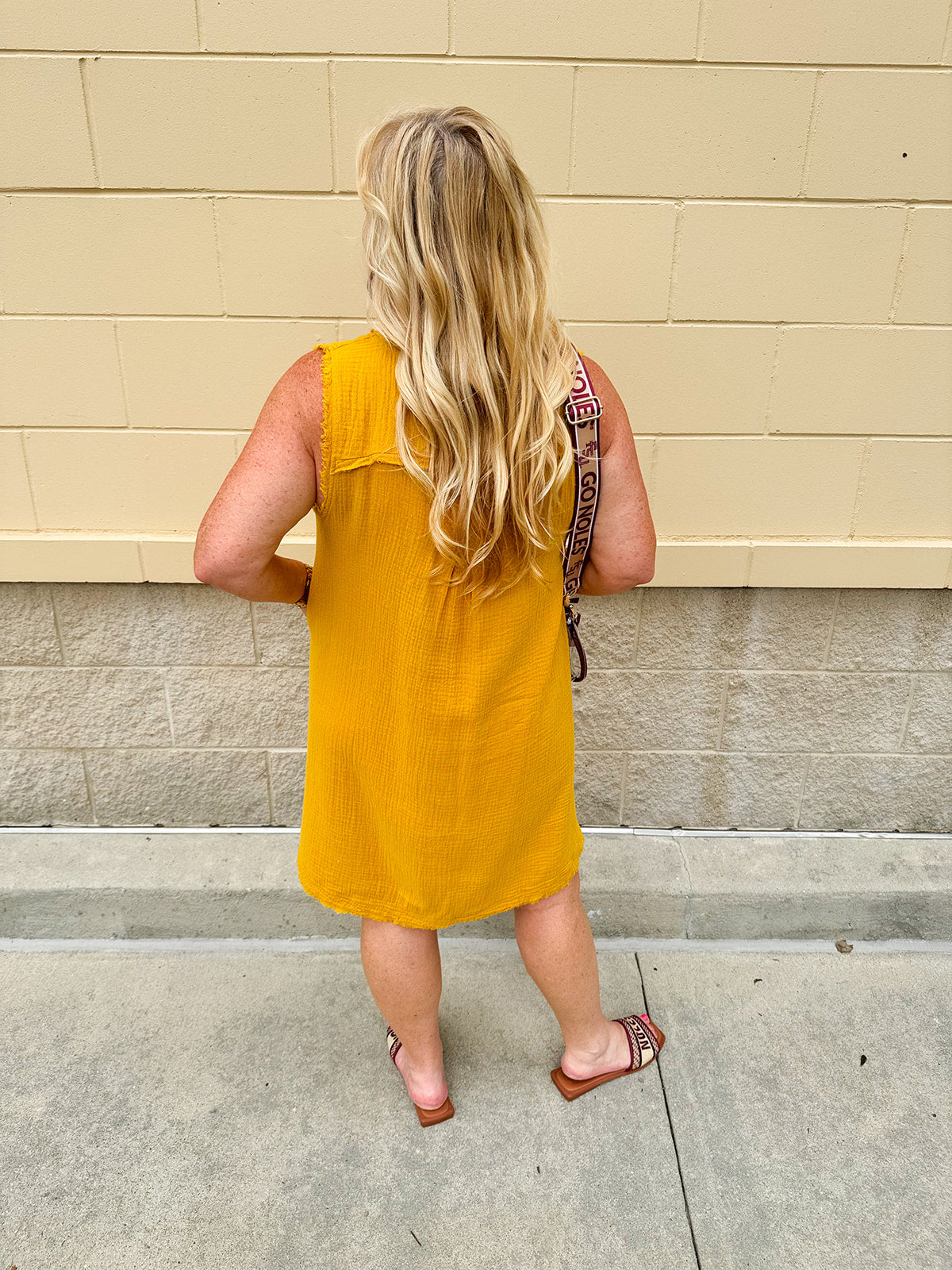 Sleeveless mustard cotton gauze dress with V-neckline, raw frayed edges, and front pockets. Lightweight and casual—ideal for Gameday or fall outings.