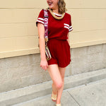 Garnet knit romper with white contrast trim on neckline, sleeves, and chest pocket. Features half sleeves, elastic waist, and keyhole back—sporty and stylish.