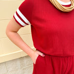 Garnet knit romper with white contrast trim on neckline, sleeves, and chest pocket. Features half sleeves, elastic waist, and keyhole back—sporty and stylish.