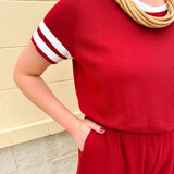 Garnet knit romper with white contrast trim on neckline, sleeves, and chest pocket. Features half sleeves, elastic waist, and keyhole back—sporty and stylish.