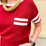 Garnet knit romper with white contrast trim on neckline, sleeves, and chest pocket. Features half sleeves, elastic waist, and keyhole back—sporty and stylish.