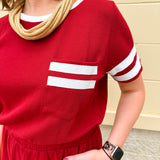 Garnet knit romper with white contrast trim on neckline, sleeves, and chest pocket. Features half sleeves, elastic waist, and keyhole back—sporty and stylish.