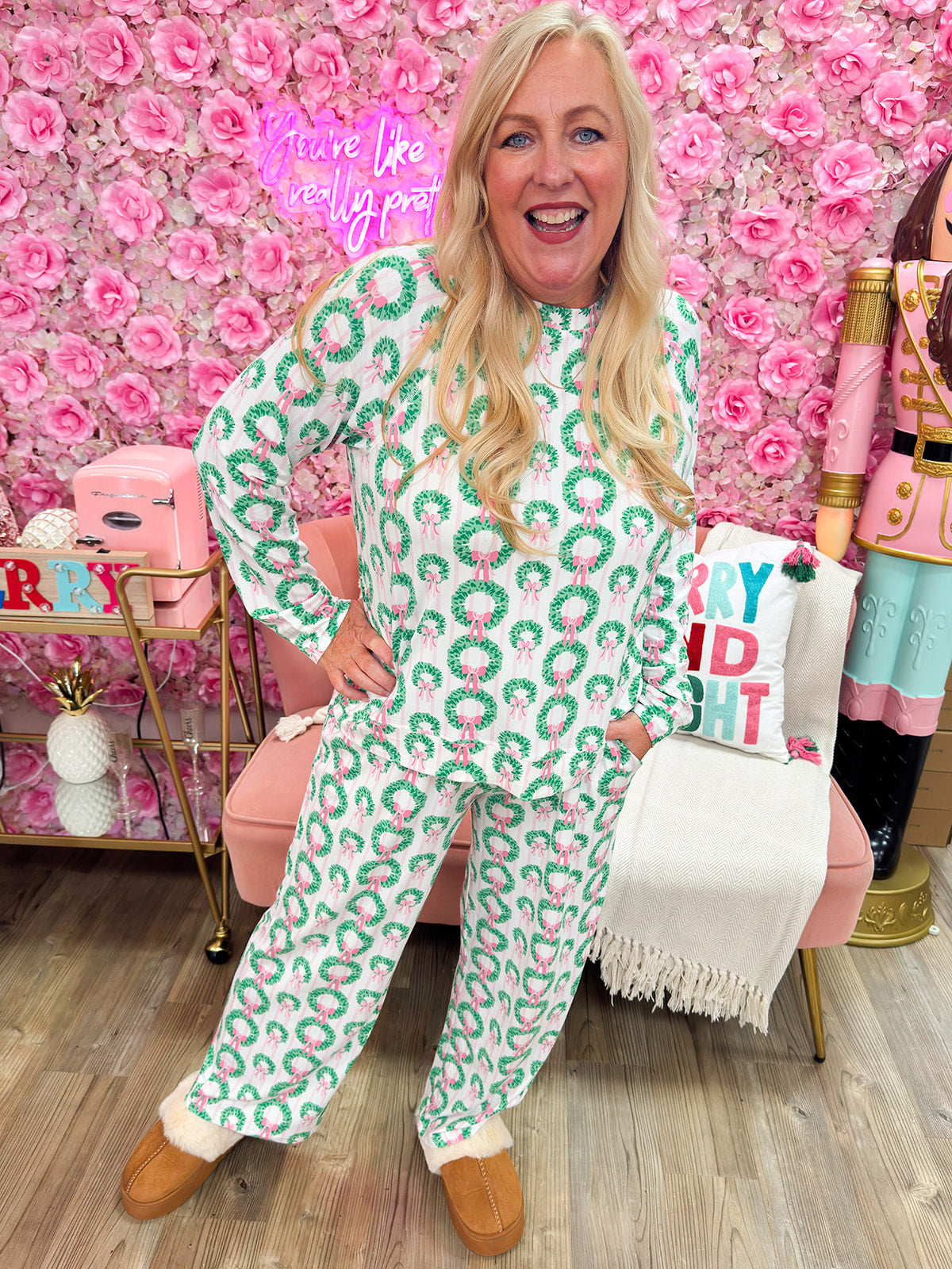 Pink and white striped pajama set with green wreath and pink bow pattern, long-sleeve top, and drawstring pants.