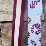 Reversible garnet and gold FSU bag strap with floral print and stripes, featuring brass hardware.