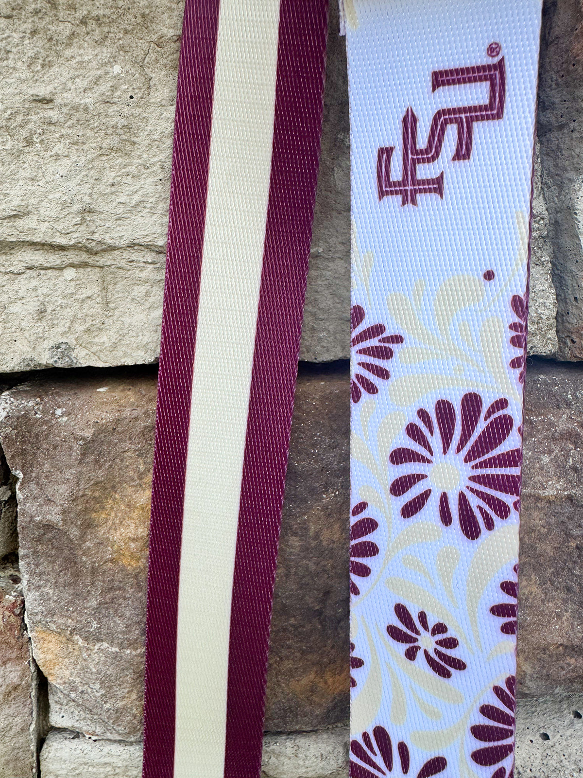 Reversible garnet and gold FSU bag strap with floral print and stripes, featuring brass hardware.