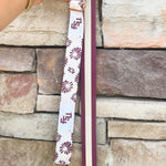Reversible garnet and gold FSU bag strap with floral print and stripes, featuring brass hardware.