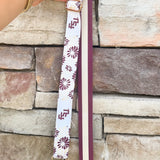 Reversible garnet and gold FSU bag strap with floral print and stripes, featuring brass hardware.