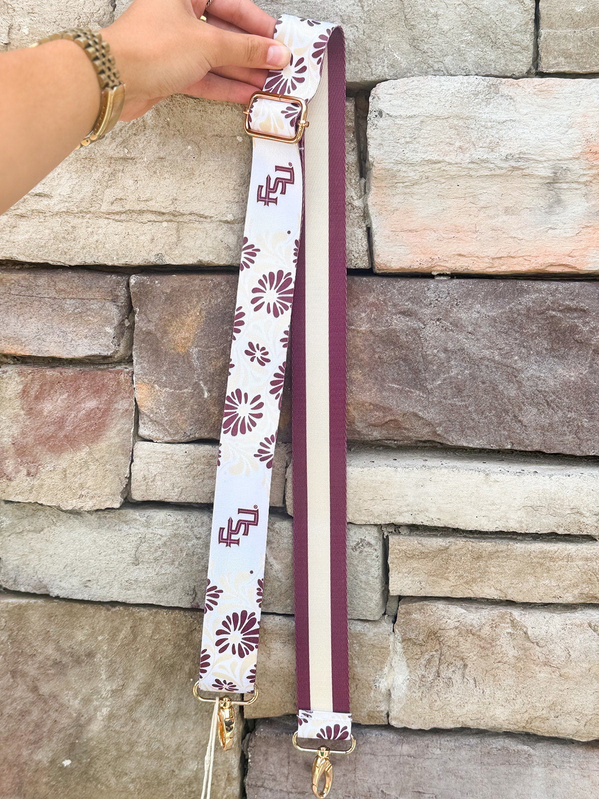 Reversible garnet and gold FSU bag strap with floral print and stripes, featuring brass hardware.