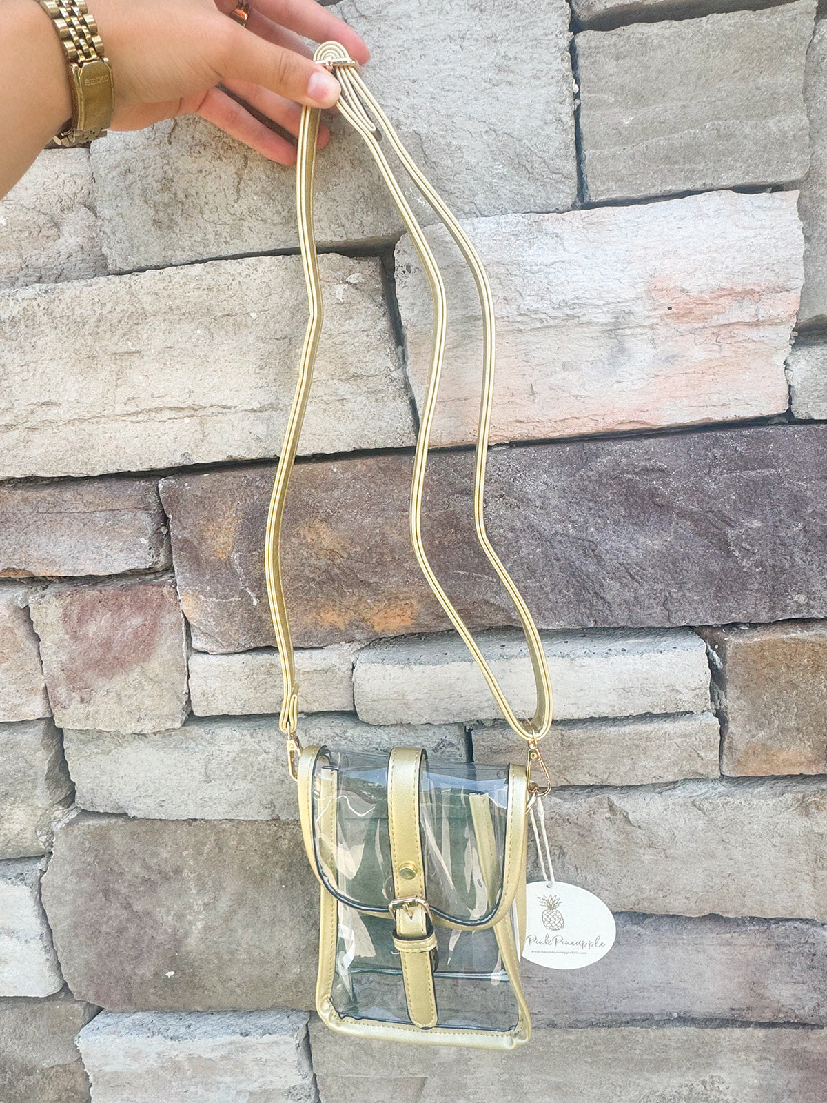Clear crossbody bag with gold faux leather trim and belt buckle accent, perfect for stadium entry.