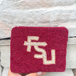 Maroon beaded clutch with FSU logo held against a stone wall.