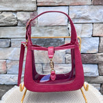Clearly Handbags Paige clear PVC crossbody bag with red vegan leather trim, gold hardware, and removable strap.