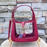 Clearly Handbags Paige clear PVC crossbody bag with red vegan leather trim, gold hardware, and removable strap.