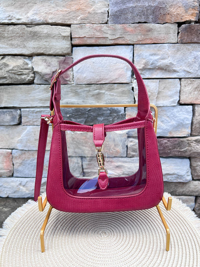 Clearly Handbags Paige clear PVC crossbody bag with red vegan leather trim, gold hardware, and removable strap.