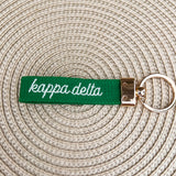 Double-sided embroidered Kappa Delta sorority keychain with white Greek letters, script sorority name, and gold hardware.