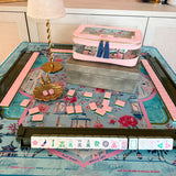 La Fête x Radiance luxury mahjong tablescape with La Fête tiles, Radiance mat, Matcha green racks, light pink tile storage bag, Blush Empress dice, gold songbird dice catchall and Aurelia rechargeable lamp