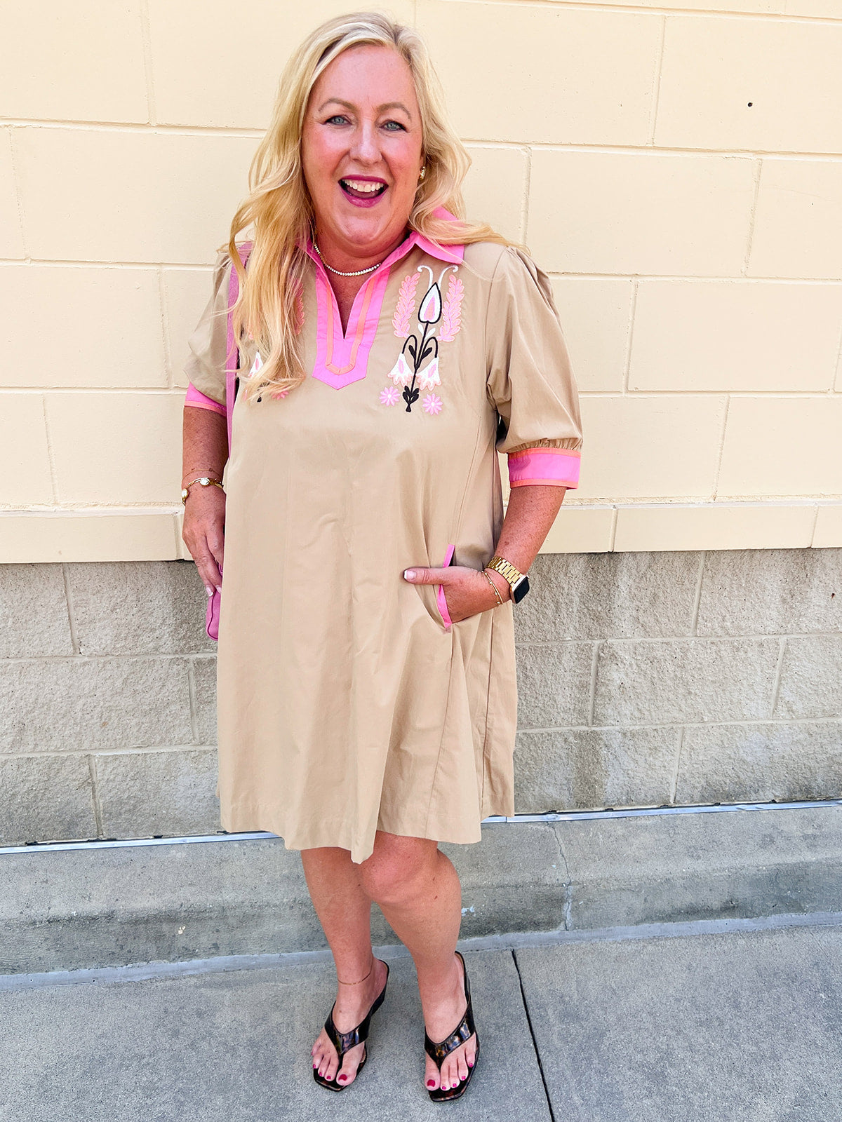 Latte midi dress with pink V-neck collar, floral neckline details, cuffed short sleeves, pink pocket trim, and pink hem.