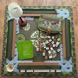 Mabel x Verdant Moss luxury Mahjong tablescape featuring olive green, blue, and brown tones with Mabel Mahjong tiles, Verdant Moss mat, Matcha Green racks, olive accessories, Maribel beaded lamp, Garden Perch dice dish, and Empress Tortoise dice.