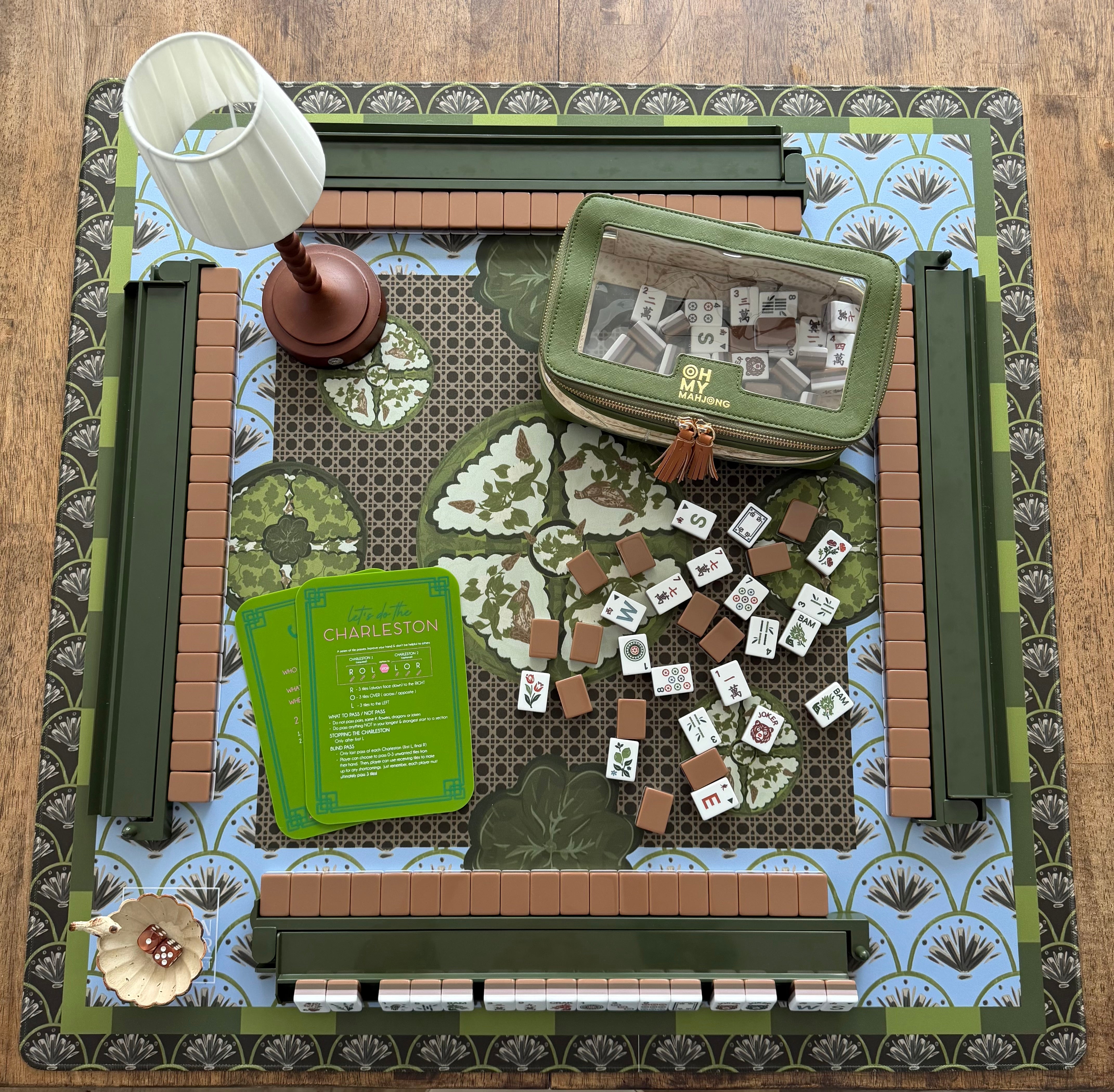 Mabel x Verdant Moss luxury Mahjong tablescape featuring olive green, blue, and brown tones with Mabel Mahjong tiles, Verdant Moss mat, Matcha Green racks, olive accessories, Maribel beaded lamp, Garden Perch dice dish, and Empress Tortoise dice.