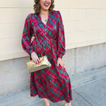 A pink, red, and green plaid tiered midi dress with ruffle neckline and long sleeves.