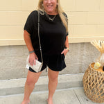 Solid black lounge set with U-neck dolman sleeve top and drawstring shorts, styled for cozy-casual wear.