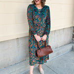 Dark teal midi dress with gold velvet floral jacquard print, long sleeves, and draped waistline.