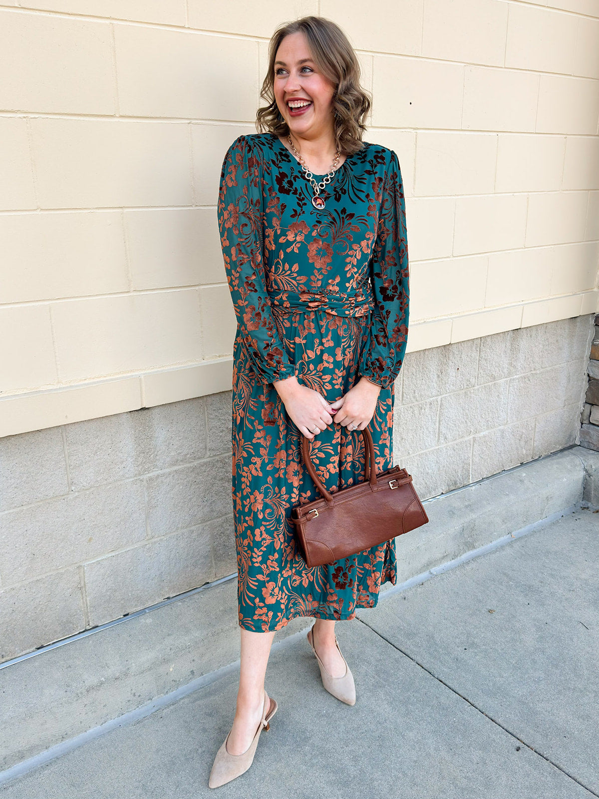 Dark teal midi dress with gold velvet floral jacquard print, long sleeves, and draped waistline.