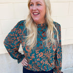 Dark teal velvet jacquard top with gold floral print, ruffled neckline, and long ruffled cuffs.