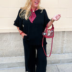 Black linen two piece set featuring ruffle sleeve top and fringe hem pants with relaxed elegant silhouette.