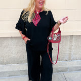 Black linen two piece set featuring ruffle sleeve top and fringe hem pants with relaxed elegant silhouette.