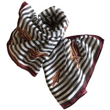 Black and white stripe mini scarf with garnet and gold spear design, styled as a headband and bag accessory