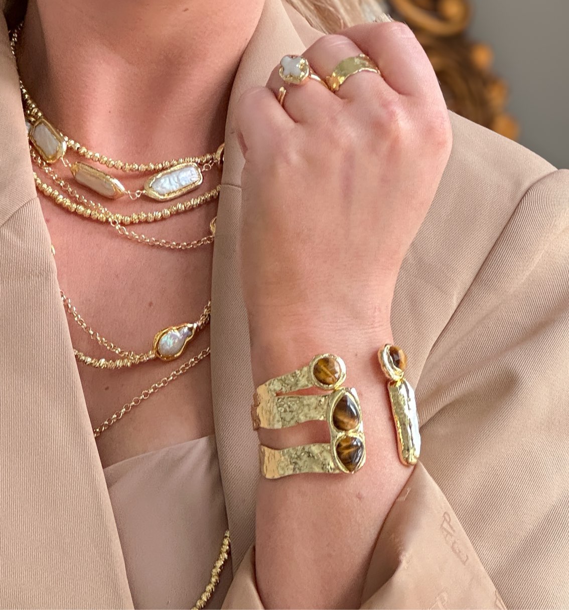 Gold cuff bracelet featuring tiger’s eye stones and a freshwater pearl accent.