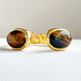 Gold open cuff bracelet featuring large tiger’s eye crystal stones on both ends.