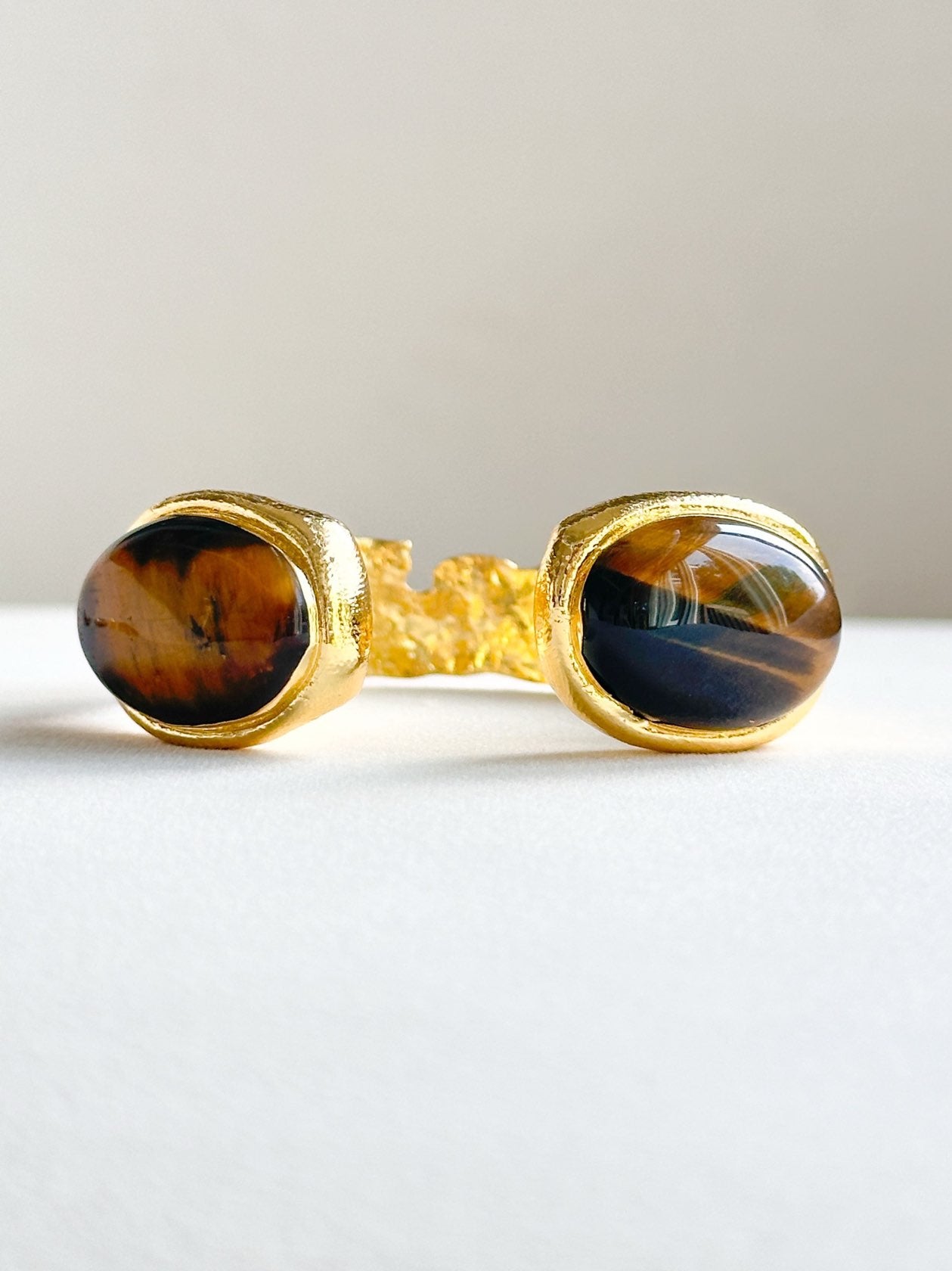 Gold open cuff bracelet featuring large tiger’s eye crystal stones on both ends.