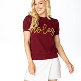 Lightweight garnet short-sleeve sweater top with gold tinsel “Noles” lettering across the chest