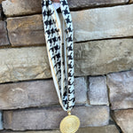 White and black houndstooth patterned scarf necklace with gold border and gold medallion pendant, handmade by Hart Designs.