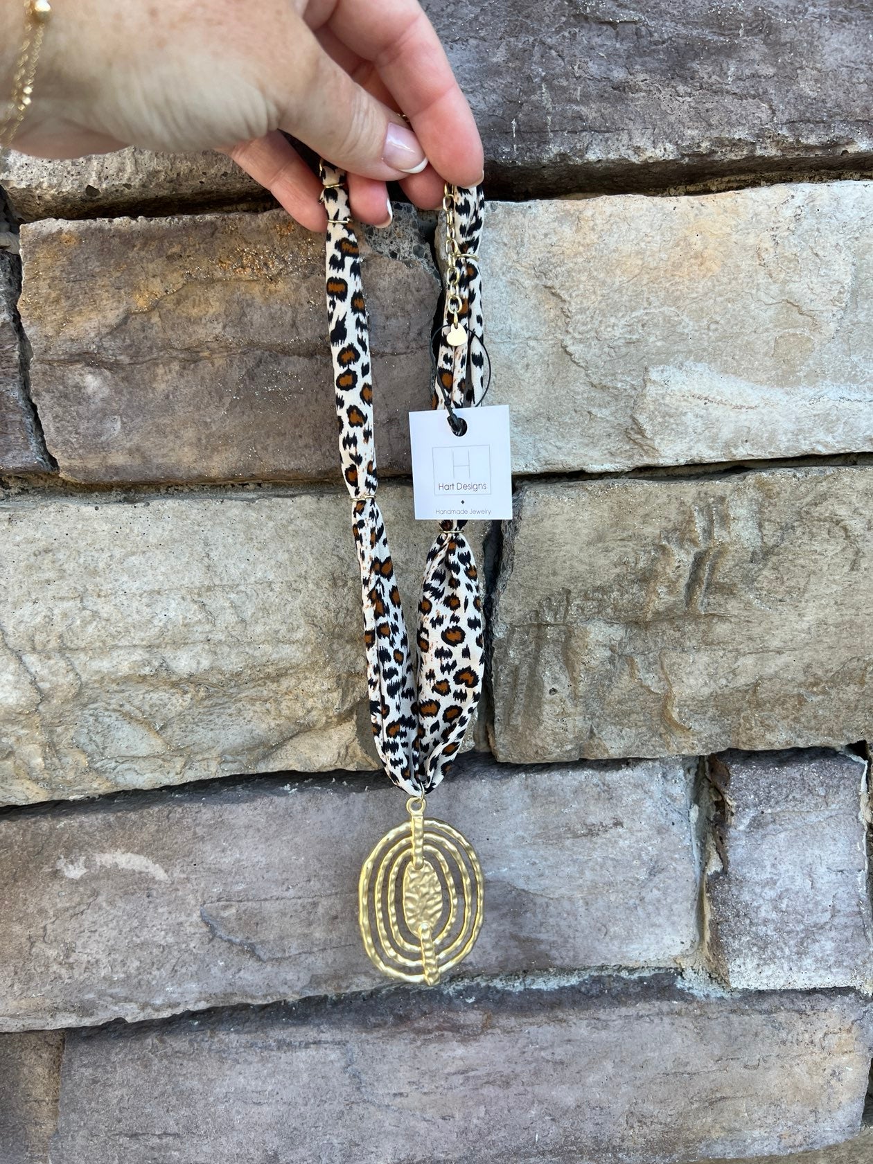 Cream, brown, and black leopard print scarf necklace with gold abstract pendant, handmade by Hart Designs.