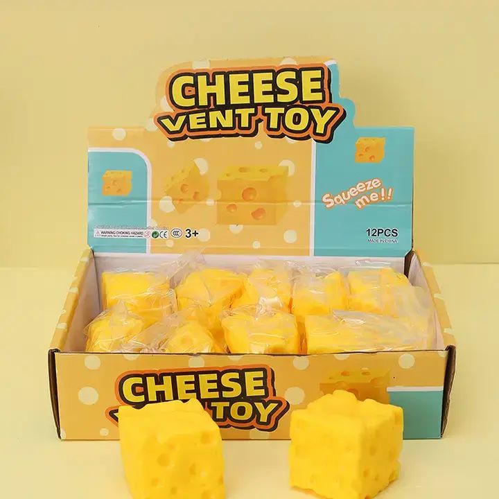 Mini cheese cube squishy toy shaped like a Swiss cheese block with soft squeezable texture and playful hole details.