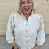 Oat velvet puff sleeve top with floral embroidery, gold buttons, and ruffle collar