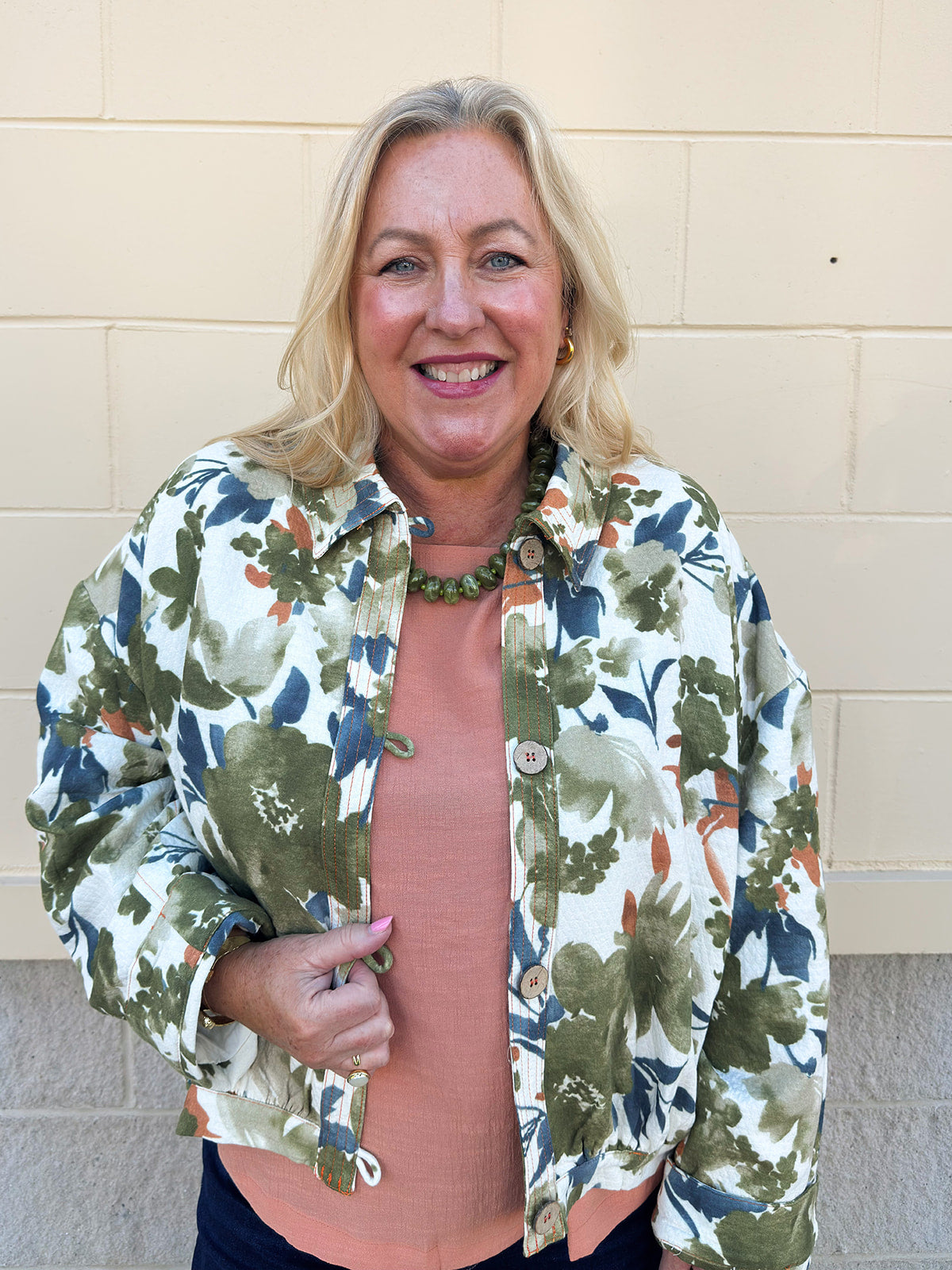 Painted Woodland Jacket featuring an olive, green, blue, and orange botanical print on a white background, a collared neckline, loop button closures, long sleeves, side pockets, and a cropped boxy silhouette.