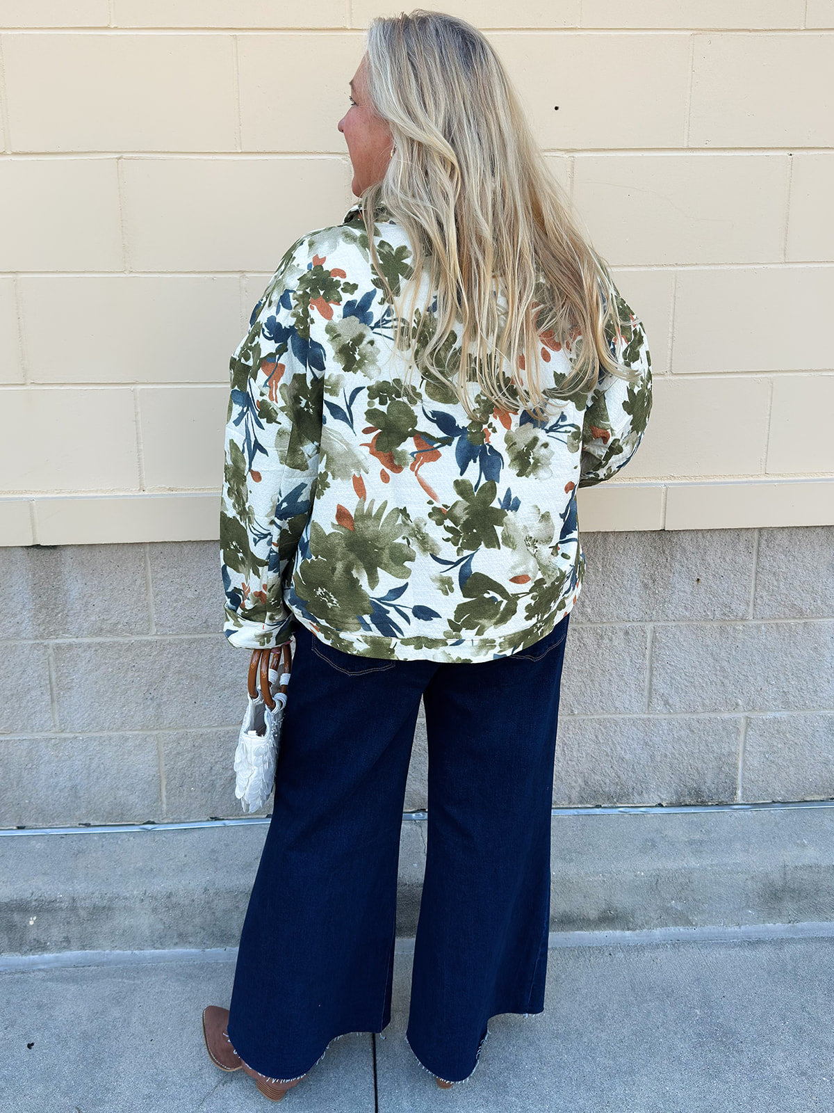 Painted Woodland Jacket featuring an olive, green, blue, and orange botanical print on a white background, a collared neckline, loop button closures, long sleeves, side pockets, and a cropped boxy silhouette.