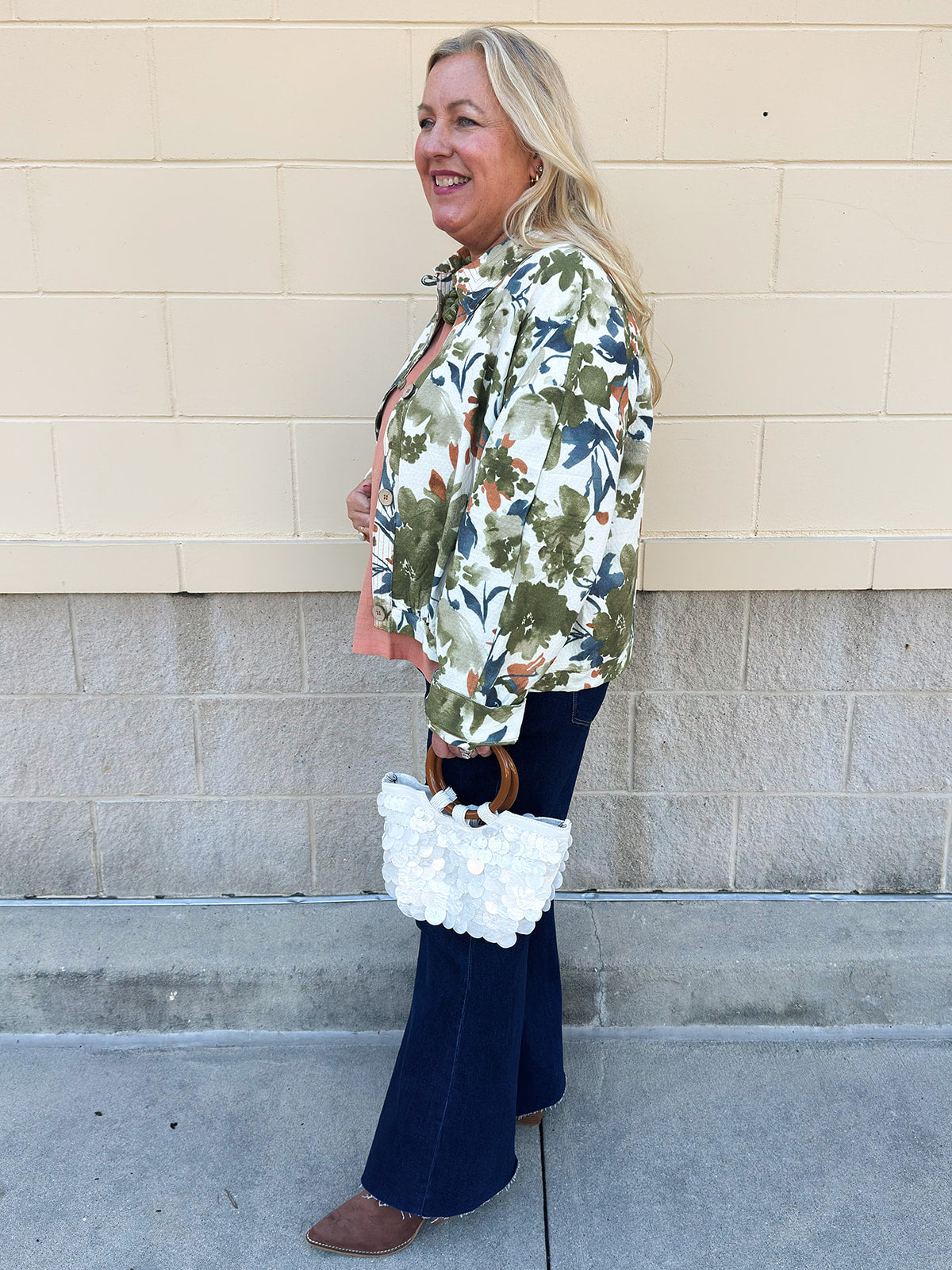 Painted Woodland Jacket featuring an olive, green, blue, and orange botanical print on a white background, a collared neckline, loop button closures, long sleeves, side pockets, and a cropped boxy silhouette.