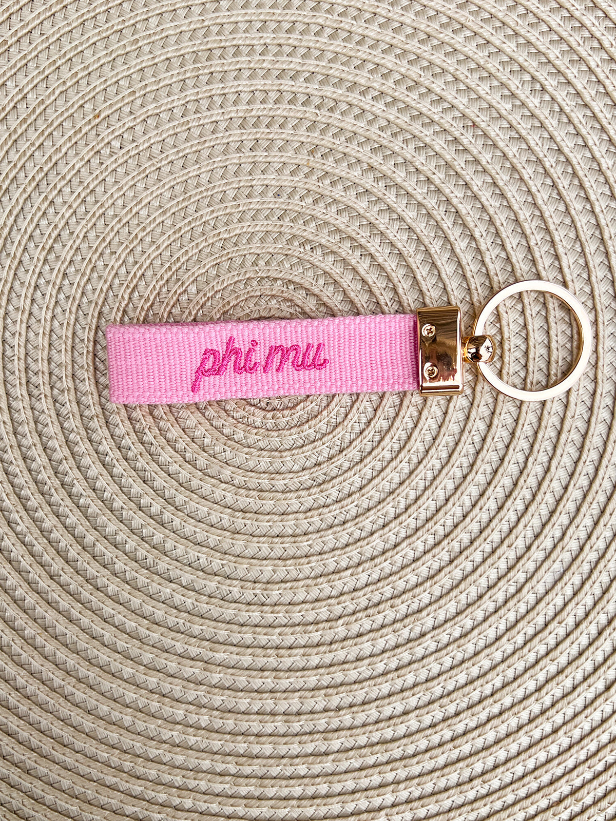 Double-sided embroidered Phi Mu sorority keychain featuring white Greek letters with a pink carnation, script embroidery on the reverse, and gold hardware.
