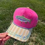 Pink faux suede and canvas snapback hat featuring an embroidered rainbow trout on the front, yellow striped brim with "Reel-y Busy" embroidery, periwinkle rope trim, fishing-themed side embroidery, and "Catch Ya Later" embroidered on the back.