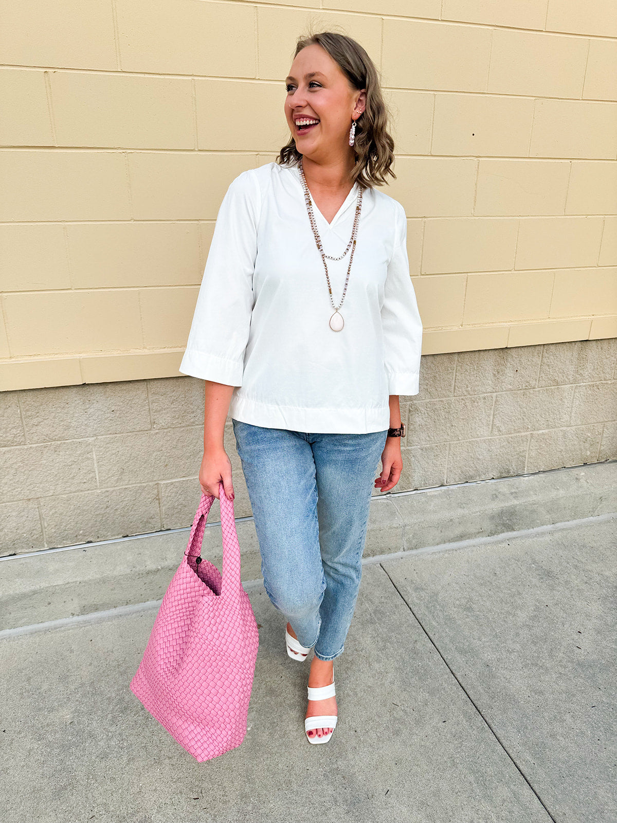White blouse with ruffled V-neck and ¾ length wide sleeves, styled for a feminine, polished look.