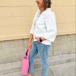 White blouse with ruffled V-neck and ¾ length wide sleeves, styled for a feminine, polished look.